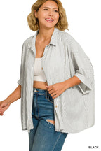 Woman in a relaxed-fit black and white striped shirt, white tank top, and blue jeans