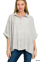 Woman wearing a relaxed black and white striped button-up shirt with wide sleeves