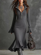 Woman in a fitted metallic knit midi dress with zip collar, ruffle cuffs and hem, holding a handbag.