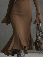 Brown knit midi dress with flared cuffs and ruffled hem, paired with brown handbag