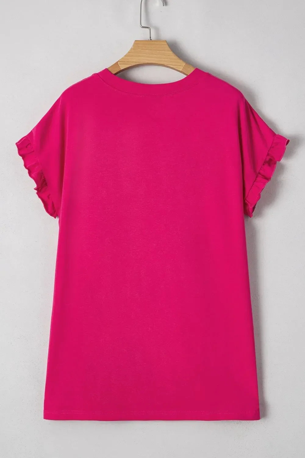 Bright pink short sleeve t-shirt with ruffle details, displayed on wooden hanger
