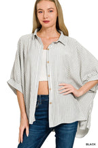 Woman wearing oversized black and white striped button-down shirt with rolled sleeves