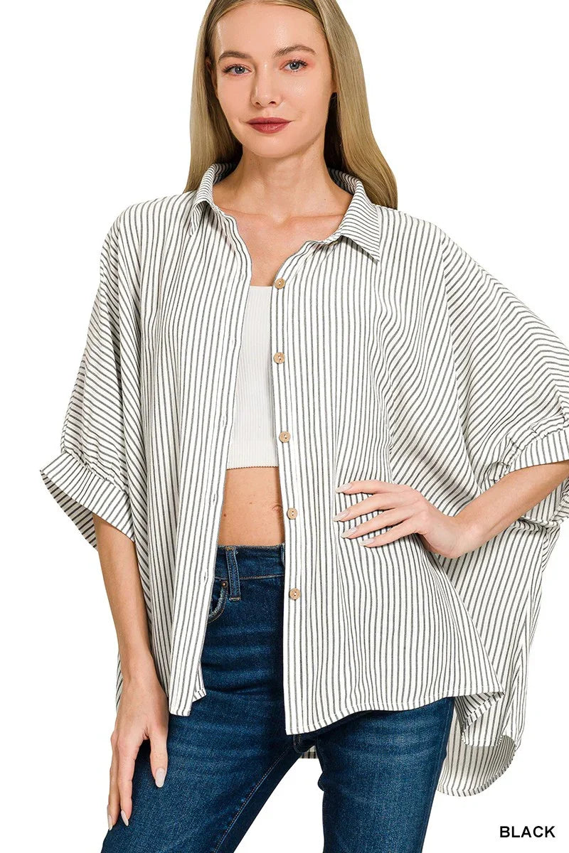 Woman wearing oversized black and white striped button-down shirt with rolled sleeves