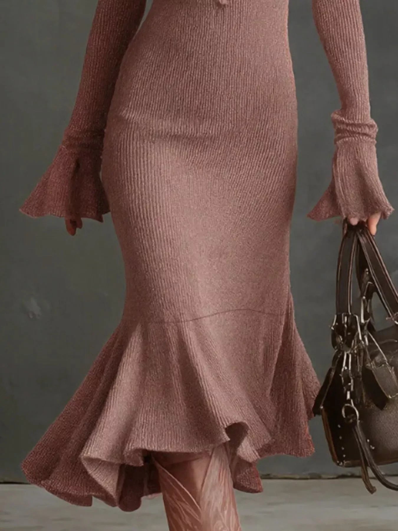 Textured pink knit midi dress with flared cuffs and ruffled hem, styled with a brown handbag