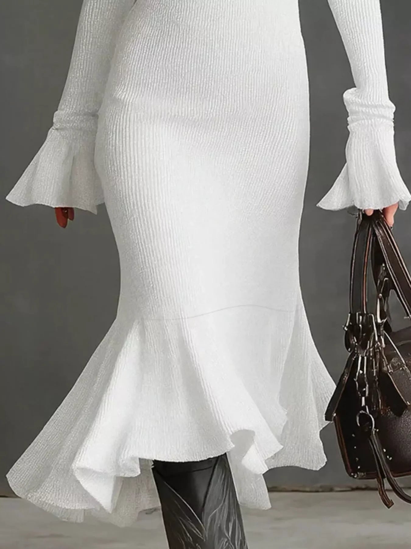 White ribbed knit dress with flounced cuffs and hem, styled with black boots and a brown handbag.