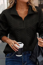 Woman wearing a black cable knit pullover sweater with half-zip collar and blue jeans