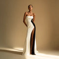 Elegant woman in a strapless white and black evening gown with thigh-high slit, fashion photoshoot