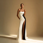Elegant woman in a strapless white and black evening gown with thigh-high slit, fashion photoshoot