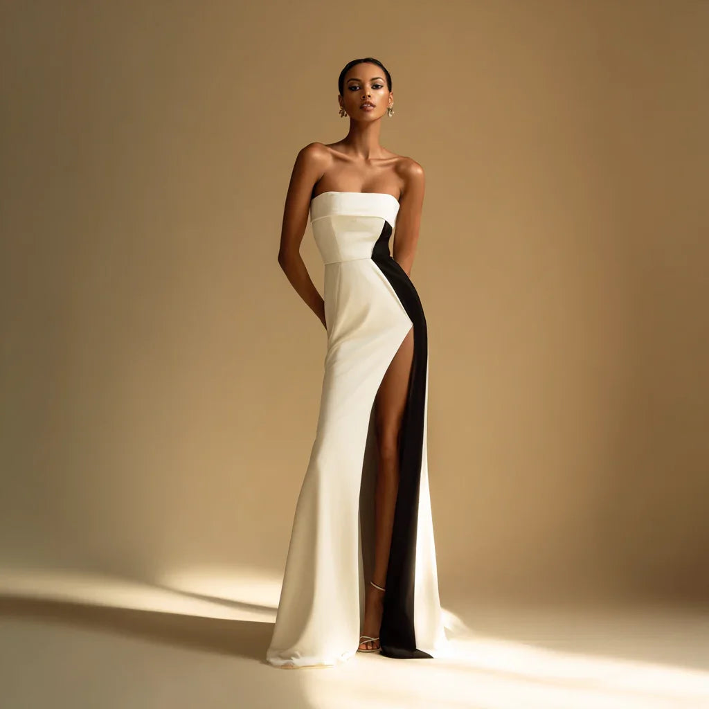 Elegant woman in a strapless white and black evening gown with thigh-high slit, fashion photoshoot