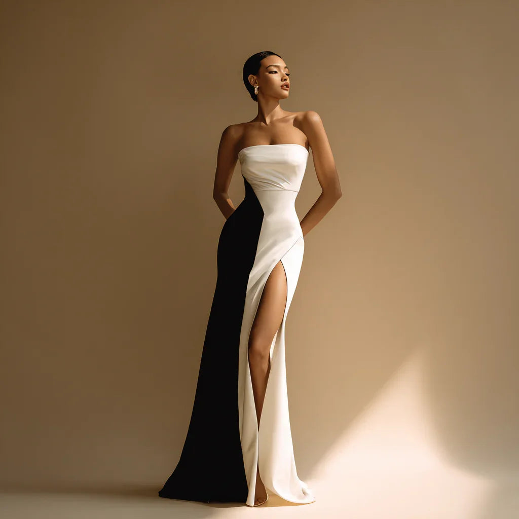 Elegant woman in black and white strapless gown with thigh-high slit, minimalist setting